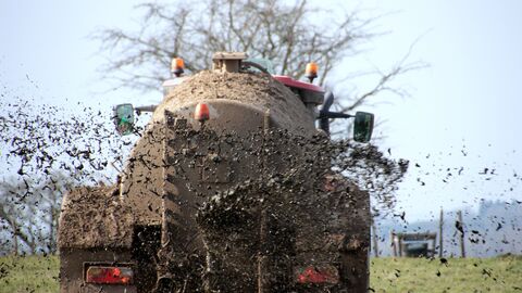 Traktor fährt auf einem Feld Gülle aus