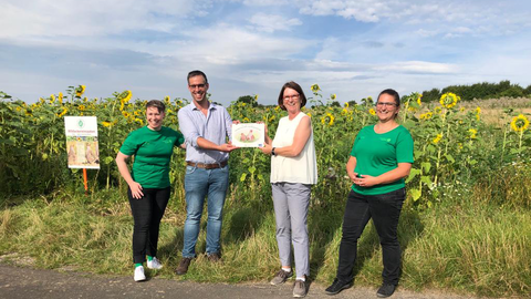 Ministernz Hinz steht gemeinsam mit Mitarbeiter*innen des Feldflurprojekt zum Schutz von Rebhühnern vor dem Feld. 