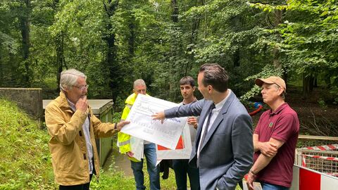 Fünf Männer stehen im Wald und schauen sich eine Karte einer Wasserfiltrationsanlage an