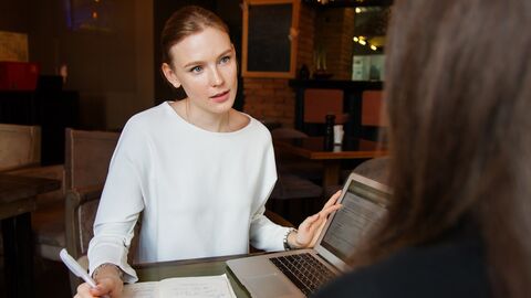 Frau hört Person zu und macht Notizen.