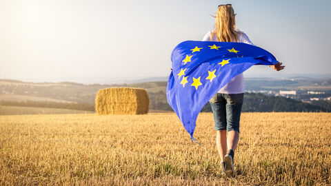 Europäische Innovationspartnerschaft Eine Frau steht mit einer Europaflagge auf einem Feld