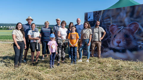 Mehrere Personen stehen vor einem großen Hamsterplakat