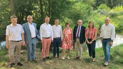 Umweltministerin Priska Hinz steht mit Lauterbachs Bürgermeister Rainer-Hans Vollmöller und weiteren Vertreterinnen und Vertretern der Stadt vor dem Brenderwasser.