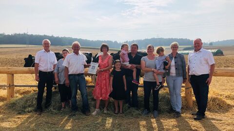 Mehrere Personen stehen vor vier angebunden Kühen