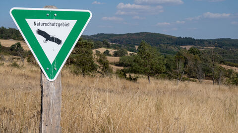 Ein Schild für ein Naturschutzgebiet vor einer Wiese