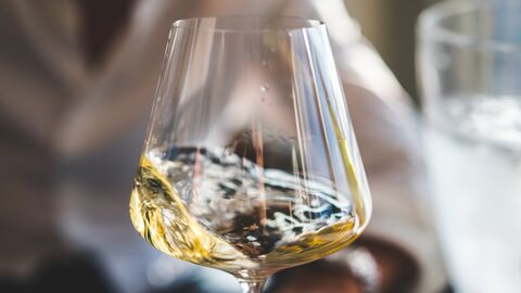 Ein Weinglas zur Hälfte gefüllt mit Weißwein