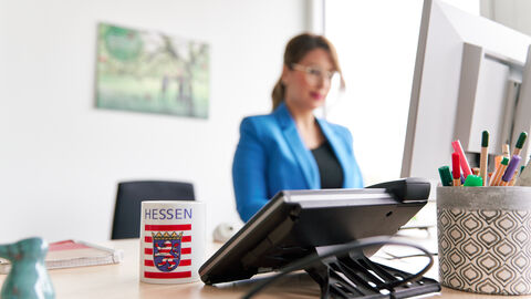 HMLU als Arbeitgeber Eine Frau mit einer Brille steht an einem Schreibtisch