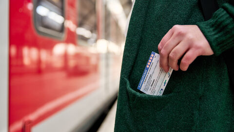 Unterwegs mit dem Landesticket Eine Frau steckt einen Fahrschein in die Jackentasche