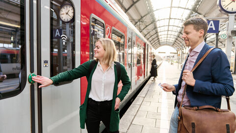 Unterwegs mit dem Landesticket Zwei Personen stehen am Bahngleis und steigen in einen Zug ein.