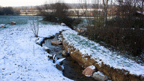 Ein Bachbett, darum Schnee