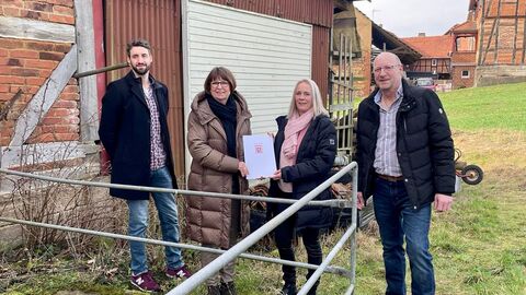 Vier Personen stehen vor einer Scheune. Ministerin Hinz übergibt einen Förderbescheid