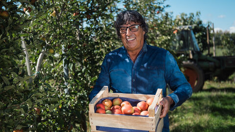 Obst und Gemüsehof Wurbs Ein Mann hält eine Kiste mit roten Äpfeln in der Hand.