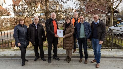 Mehrere Personen stehen auf einer Brücke. Ministerin Hinz übergibt einen Bescheid.