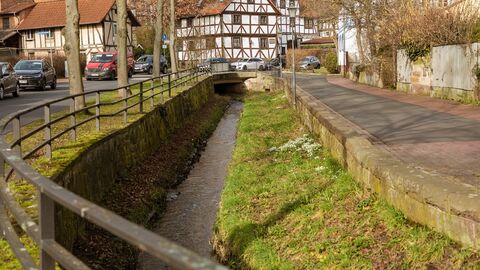 Ein kanalartiges Bachbett in einem Ort. Rechts und links davon Straßen