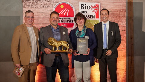 Oliver Conz bei der Verleihung des Goldenen Qualileo Vier Personen stehen nebeneinander. Ein Mann hält einen goldene Löwenstatue in der Hand.