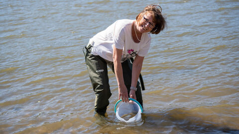 Eine Frau steht mit einem Eimer im Fluss