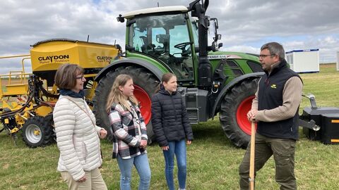 Freiluft Klassenzimmer auf dem FuldaAcker Vier Personen stehen vor einem Traktor auf einem Feld