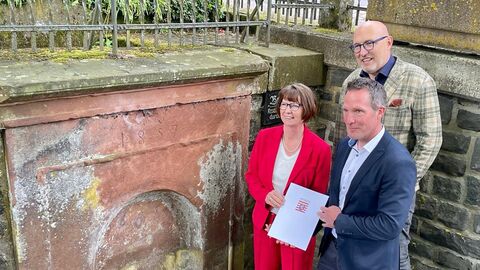 Drei Personen stehen an einer Wasserstelle in der Stadt