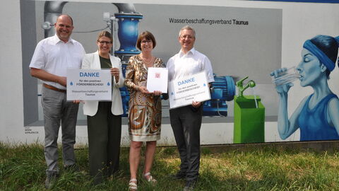 4 Personen (m,w,w,m) halten einen Übergagbebescheid, sowie ein Plakt mit Danksagungen in den Händen.