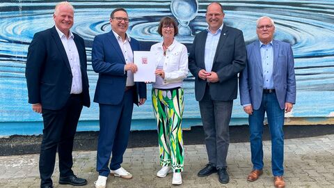 5 Personen schauen in die Kamera. In der Mitte Ministerin Hinz (weiß/grün) mit Förderbescheid mit Hessen Wappen.