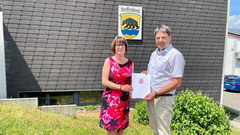 Eine Frau und ein Mann halten einen Förderbscheid in der Hand