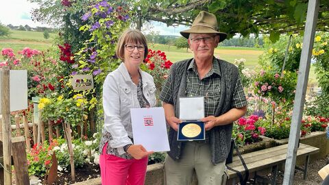Eine Frau und ein Mann stehen vor blühenden Sträuchern