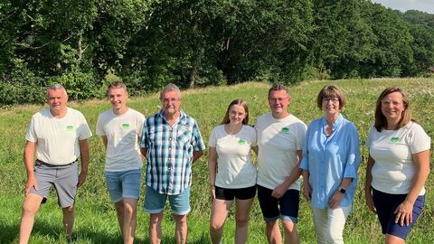 Ministerin Priska Hinz mit Familie Platzdasch vom Quellwiesenhof auf einer Wiese.