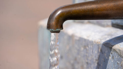 Wasserversorgung Wasser fließt aus dem Hahn eines öffentlichen Brunnens