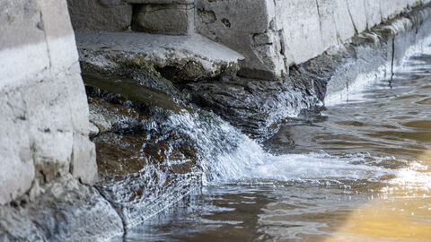 Wasserleitung Wasser fließt aus einem Kanal in einen Fluss