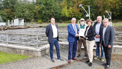6 Personen vor einer Kläranlage bei der Übergabe eines Förderungsbescheids.