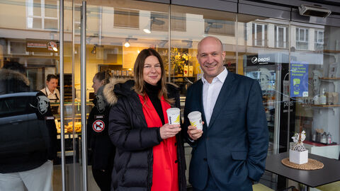 Zwei Personen (Minister Ingmar Jung und Wiesbadens Umweltdezernentin Christiane Hinninger) mit Mehrwegbecher vor teilnehmender Bäckerrei.