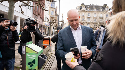 Umweltminister Ingmar Jung scannt QR-Code des Bechers. 