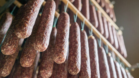 Würste hängen zum Trocknen an Fäden