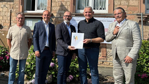 Staatssekretär Daniel Köfer (3.v.l.) übergibt vor Ort den Förderbescheid.