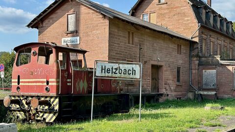Altes Bahnhofsgebäude, davor eine alte, rote Lock