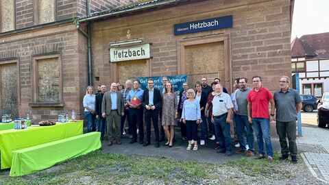 Mehrere Menschen vor altem Bahnhofsgebäude