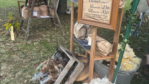 Stand mit Schafwolle und Verkaufsschild.