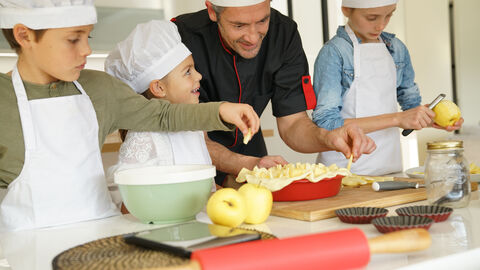 Pastry class with kids little chefs Drei Kinder kochen mit einem Koch.