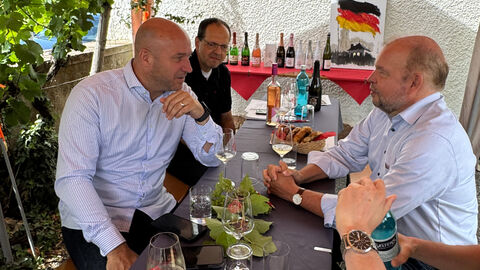 Beim Weingut Bibo Runge tauscht sich Weinbauminister Ingmar Jung mit Dr. Keith Ulrich, Vorstandsvorsitzender „Fair and Green e.V.“, aus. Weinbauminister Ingmar Jung sitzt mit Dr. Keith Ulrich, Vorsitzender des Vereins Fair and Green, an einem Tisch.