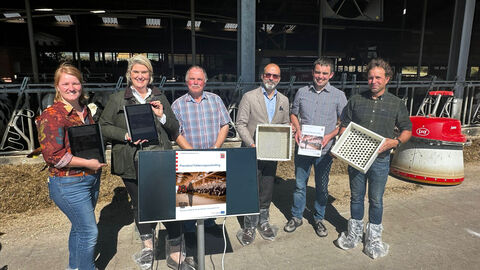 Sechs Personen stehen zusammen vor einem Bildschirm.