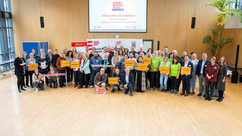 Eine große Gruppe Menschen vor einer Leinwand.