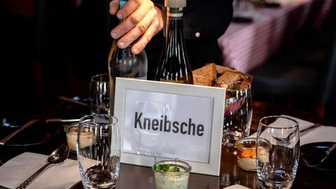 Aufnahme eines Tisches mit Gläsern, Besteck und Snacks. In der Mitte ein Schild mit der Aufschrift "Kneibsche".