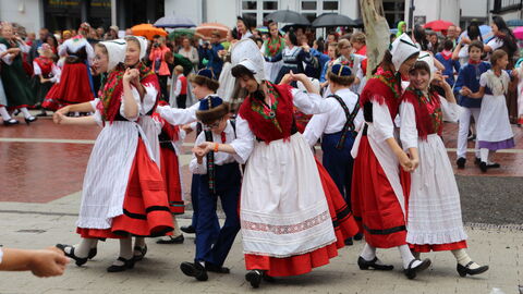 Eine Gruppe in Tracht tanzt auf einem Platz vor Publikum.