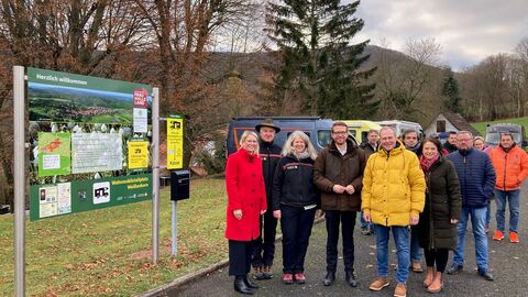 eine Gruppe von Menschen auf einem Parkplatz vor Wohnmobilen.