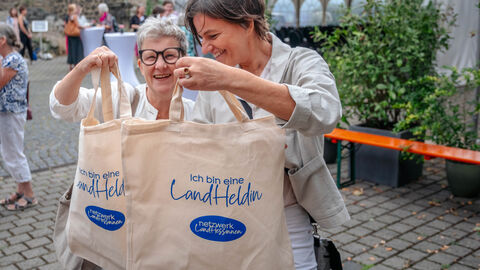 Frauen halten Taschen mit dem Aufdruck "Landheldin" hoch.