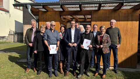 Eine Gruppe Menschen vor der Terrasse eines Dorfgemeinschaftshauses.